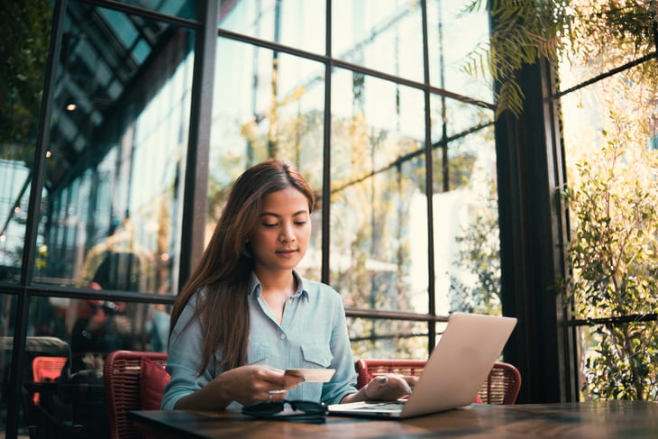 Asian woman doing online shopping in a cafe on her laptop