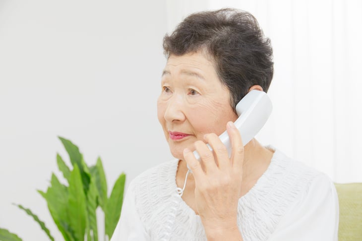 An older woman talks on a landline phone