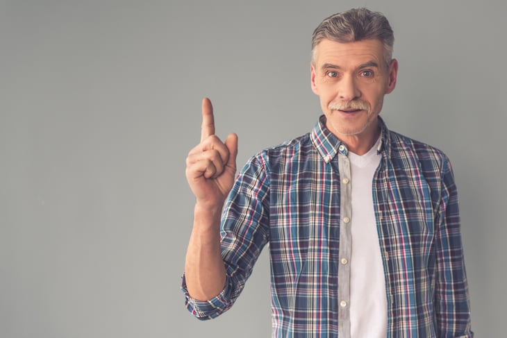 A senior man gestures with his index finger