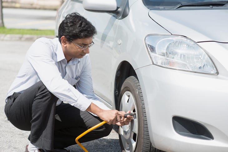 Driver checking tire pressure