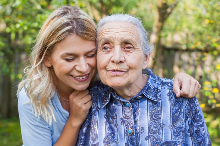 A young woman hugs her grandmother outdoors