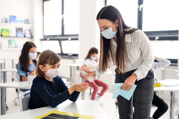 A teacher helps a student with face masks on during the coronavirus crsis