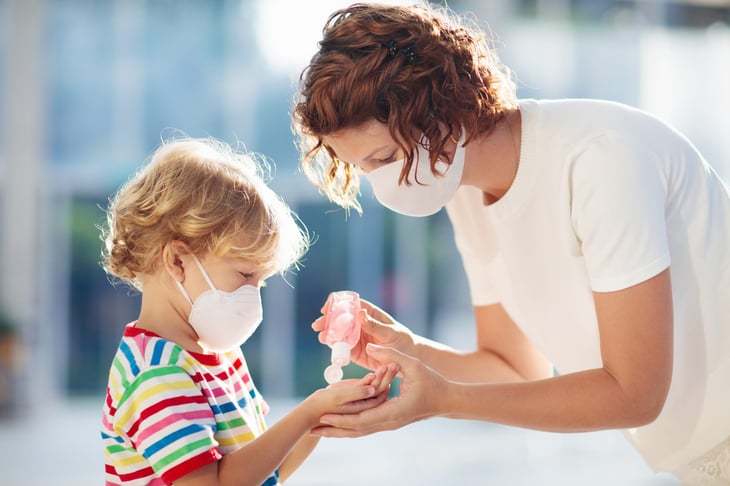 Parent and child use hand sanitizer and face masks at school