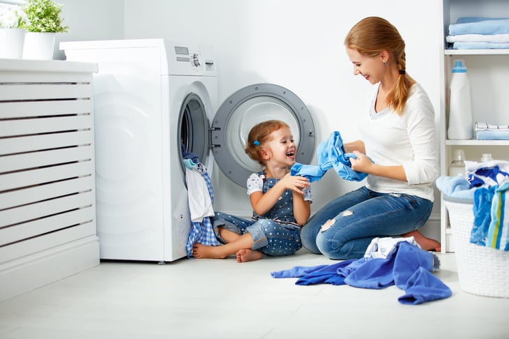 A mom and child load a washing machine