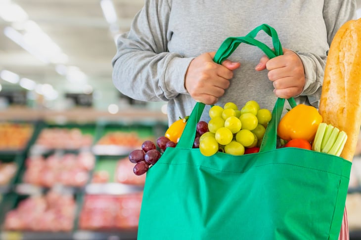 Man holding a reusable bag filled with groceries