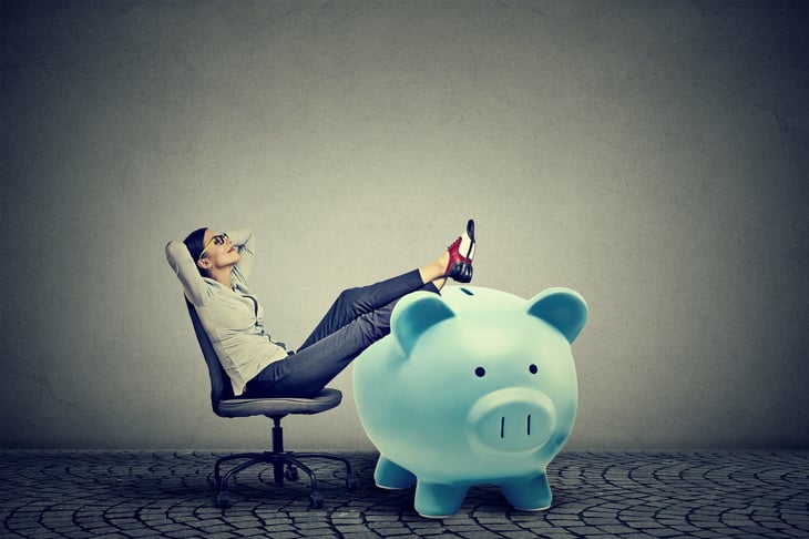 A woman relaxes with her feet up on a fat piggy bank
