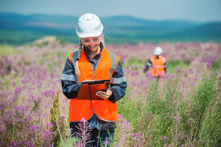 woman scientist hard hat clipboard Researching recultivated field