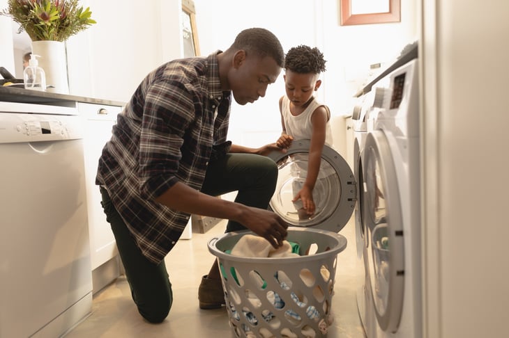 A father and son wash clothes in their laundry room