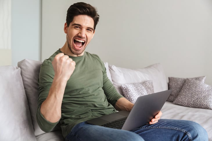 A happy man celebrates making an online purchase