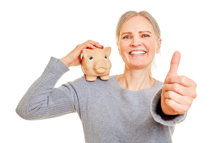 Senior with piggy bank holds her thumbs up