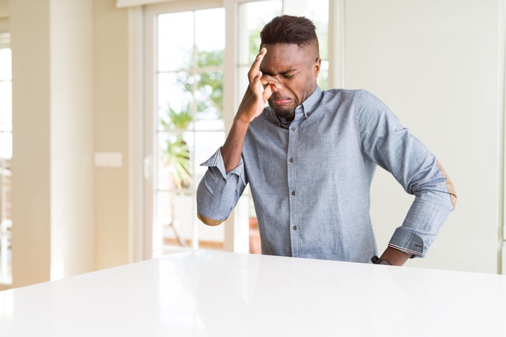 Man holding his nose to avoid a bad smell in his home