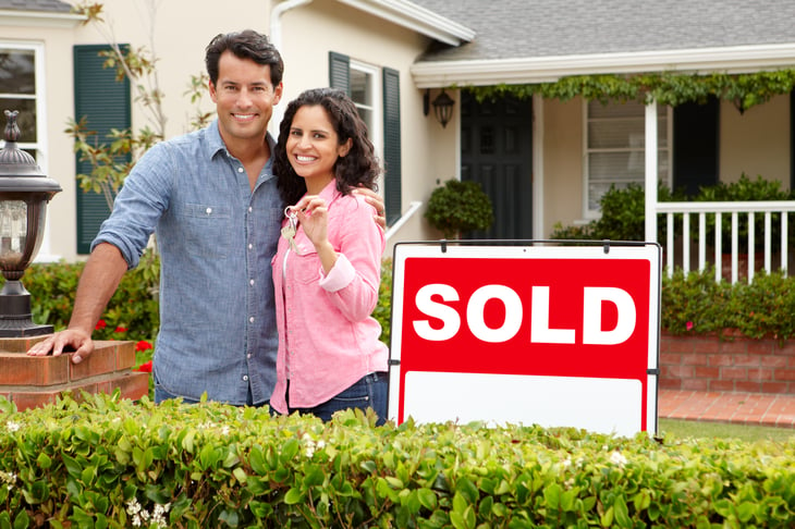 Couple in front of a home with a sold sign