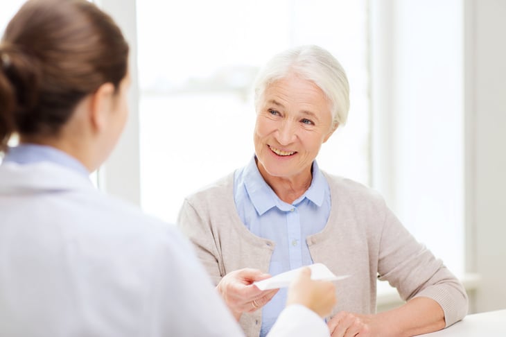 A doctor gives a prescription to a senior patient