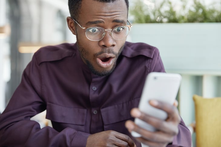 man in glasses is surprised by something on his smartphone