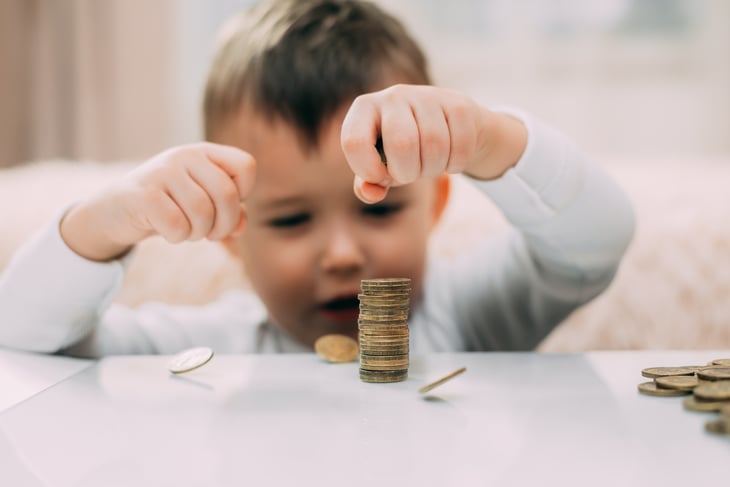 A baby plays with coins