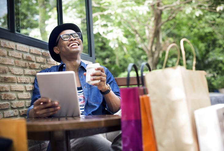 Shopper using a tablet and drinking coffee at a restaurant outdoors