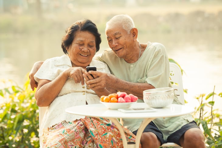An older couple uses a phone outside