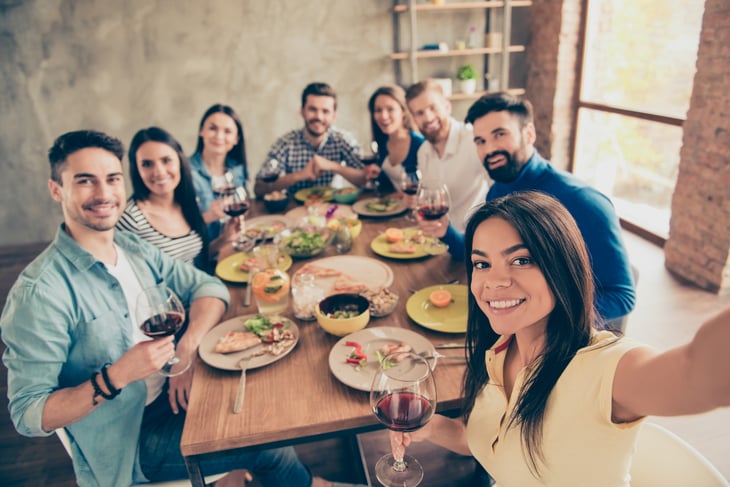 woman takes a selfie with friends at the dining table
