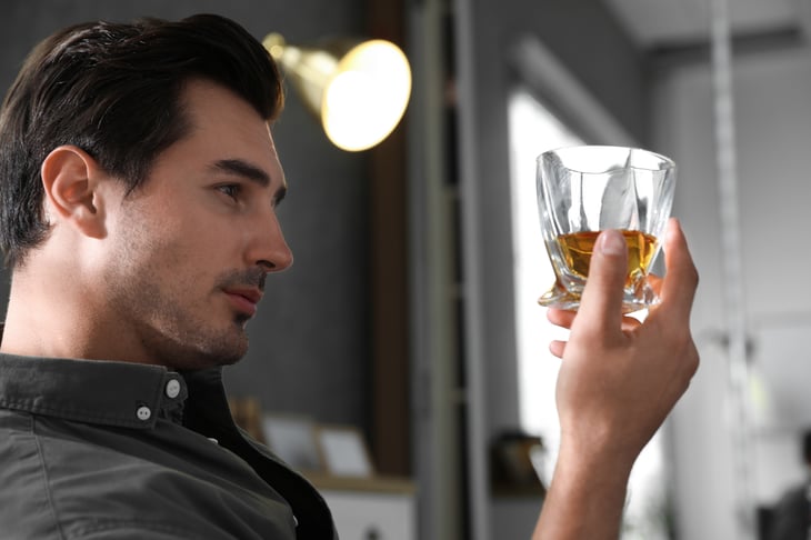 A man drinks a glass of whisky