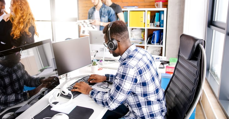 Typist working at a computer while wearing headphones