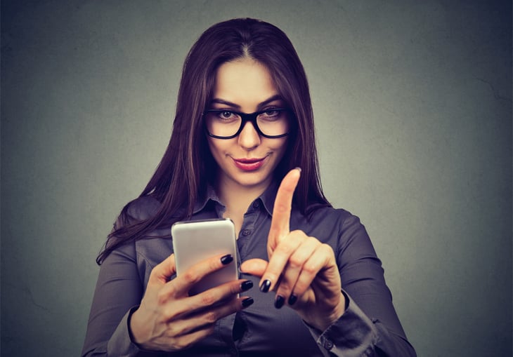 Young woman with smartphone showing no attention with hand gesture.