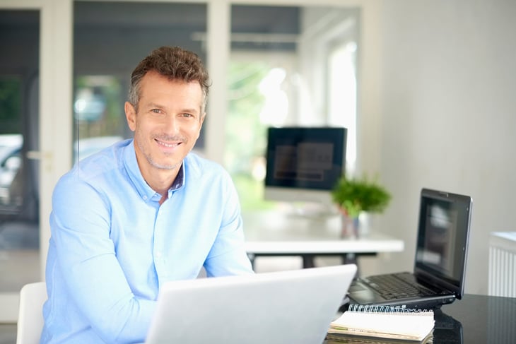 An older man works on a laptop computer at his desk