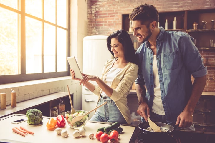 A couple cooks a meal at home