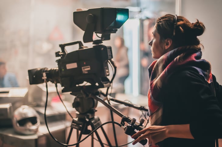 A woman works behind the camera on set