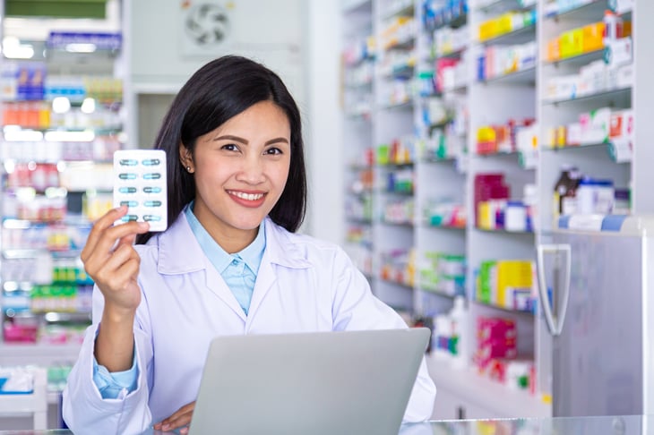 A young pharmacist holding a package of medication