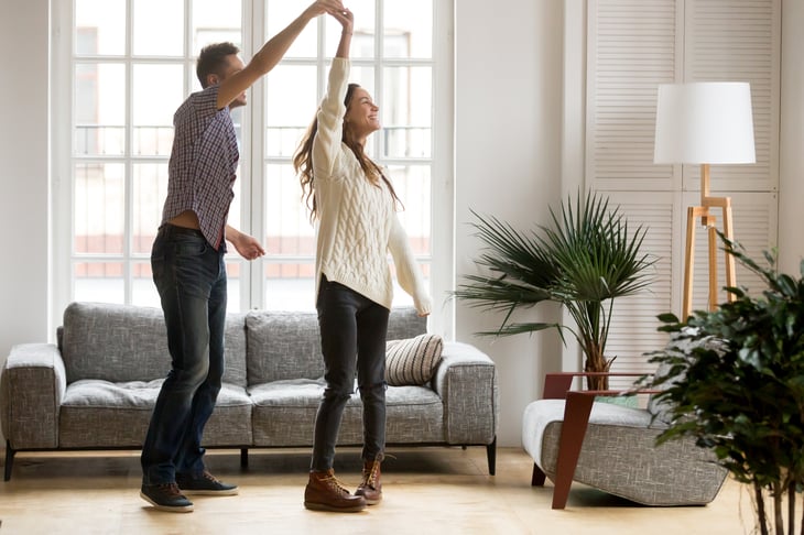 A happy young couple dances in their living room