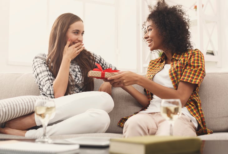 A young black woman gives a holiday gift to a girlfriend
