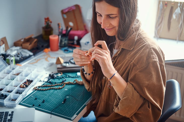 A woman handcrafts jewelry with beads