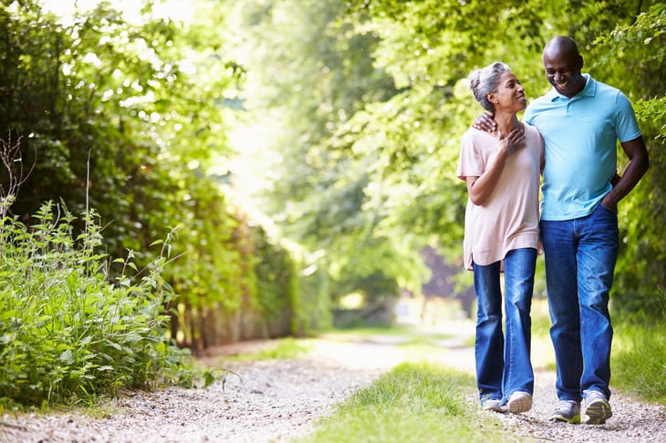 An older black couple gets exercise by walking outdoors