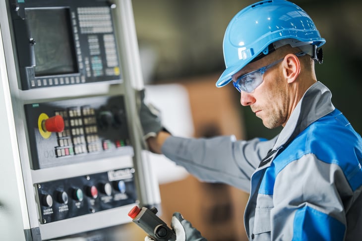 A man working a control panel in a hard hat