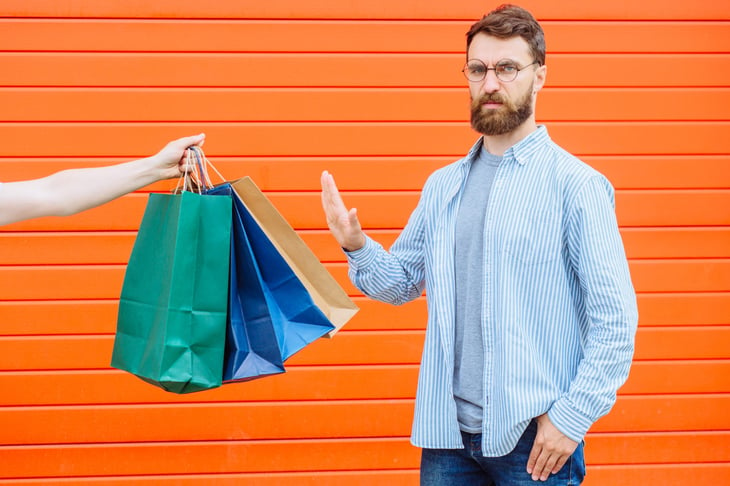 Man giving the stop gesture to shopping bags