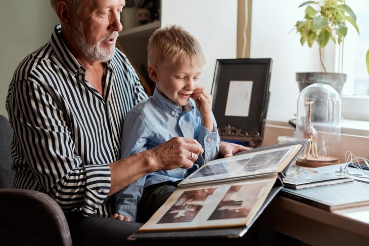 Grandfather and grandson looking at old family photos and genealogy