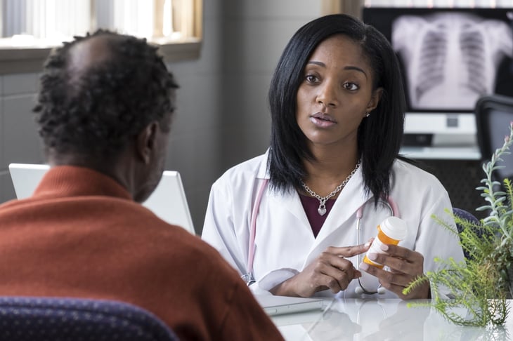 A black female doctor prescribing pills to an older black male patient