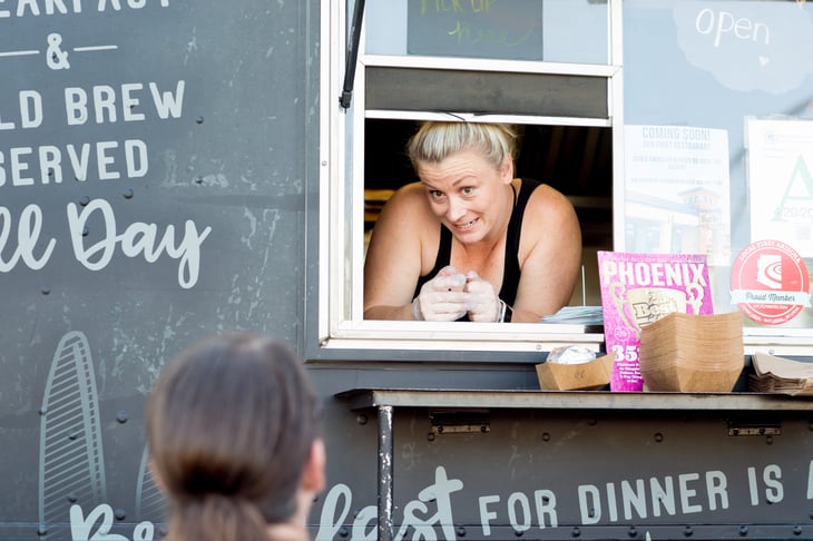 Smiling woman vendor leaning out of food truck talking to customer