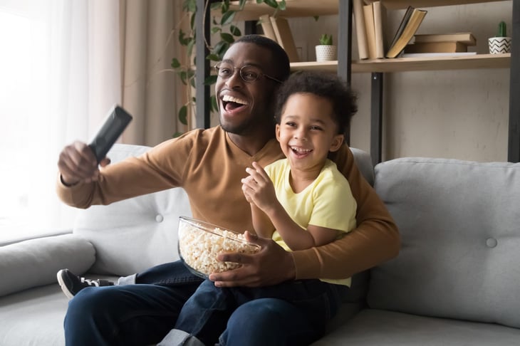 A dad and kid watch tv