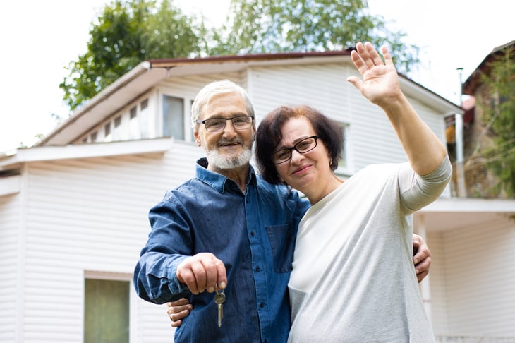 Retired couple in front of their home