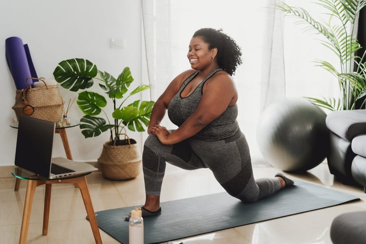Woman taking a virtual Pilates, yoga, or excercise class at home from her laptop