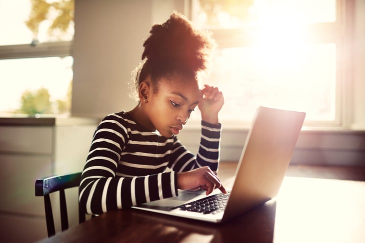 A girl studies on a laptop computer at home