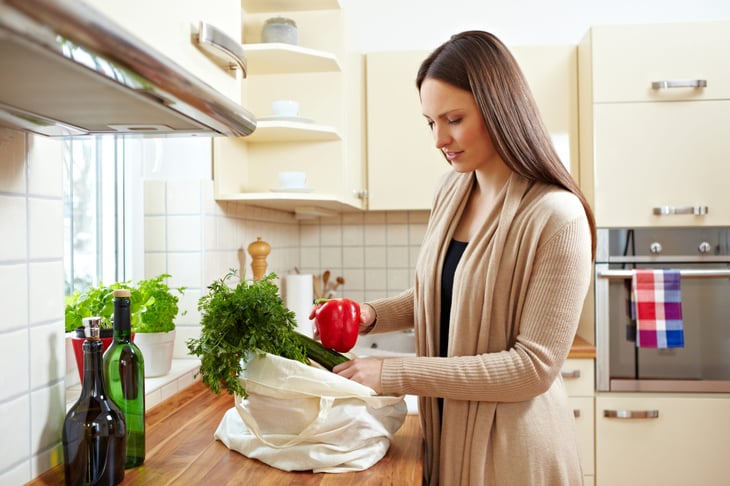 A woman unpacks groceries in her kitchen
