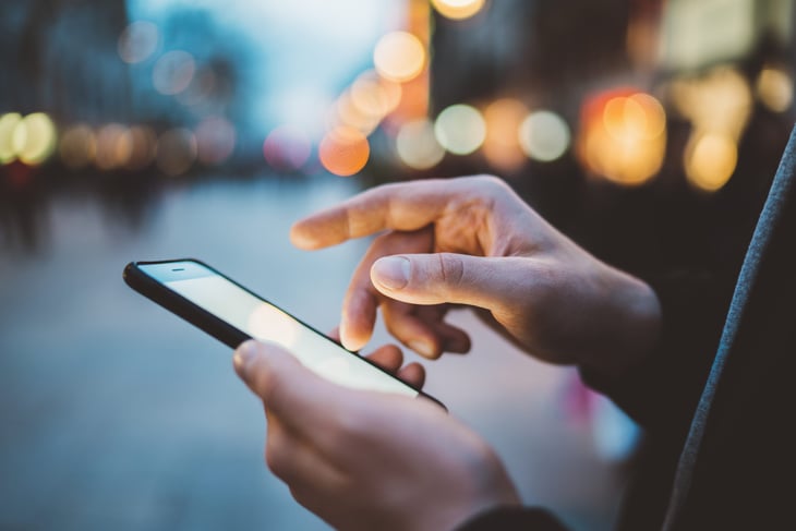 A man using a cellphone on the street for online shopping and transportation