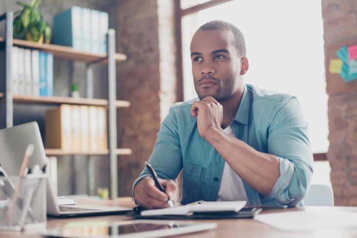 Black man at desk thinking about possibilities