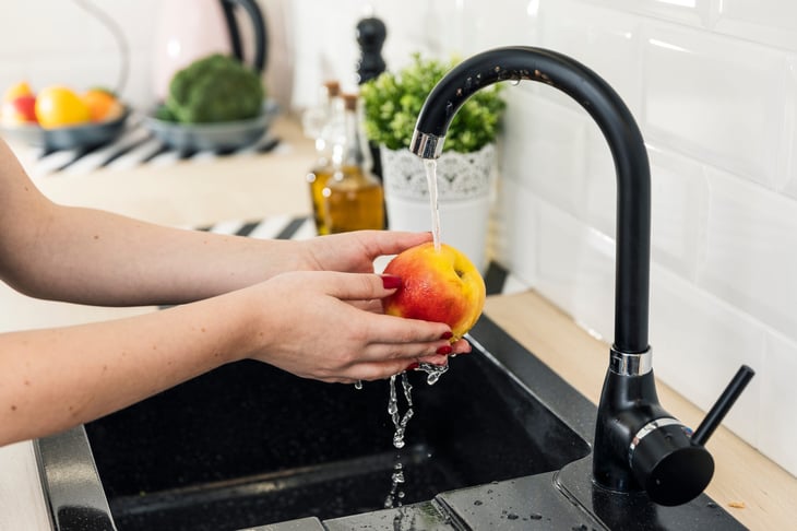 Woman washing fruit in a kitchen sink