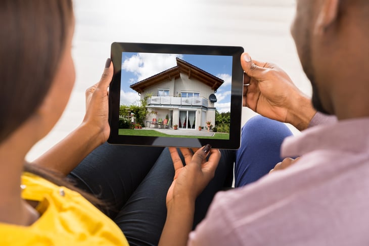 Couple looking at house on digital tablet