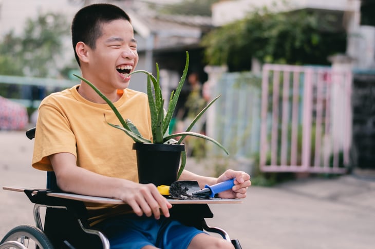 Child in a wheelchair holding an aloe vera plant