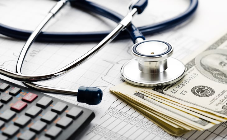 Stethoscope and cash with a calculator and tax forms for an HSA or health savings account or health insurance