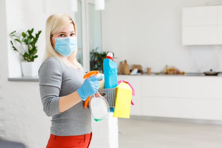 A woman in a mask with household disinfectants